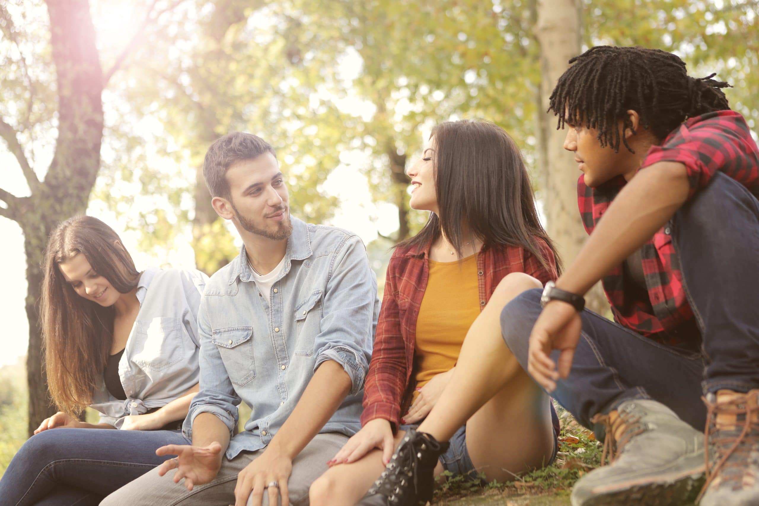 happy-multiethnic-friends-sitting-in-park