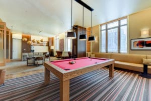 A modern room with a red pool table, seating areas, and large windows.