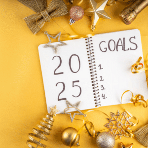 A notebook with "2025 Goals" and four blank spaces is surrounded by gold and bronze holiday decorations on a yellow background.